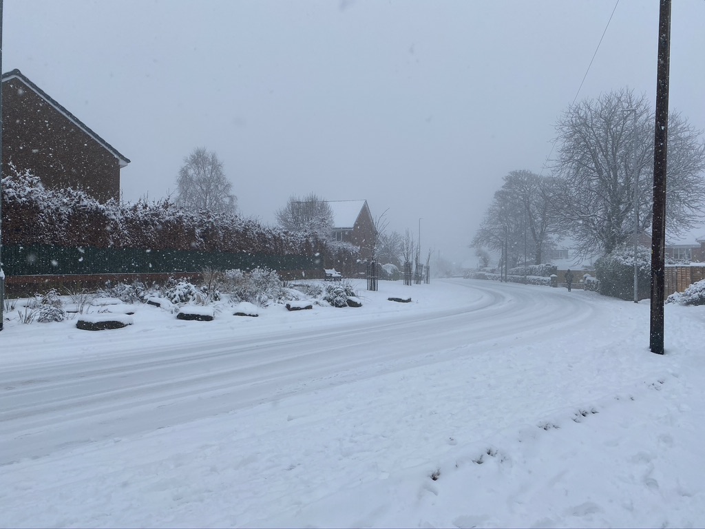 Snow on the road and landscaped area next to Hawthorne Estate